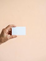 Hand holding blank white card against neutral beige background. Adult male hand displaying empty business card, membership card, or gift card for branding and marketing mockup designs.