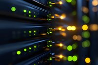 Network switch with blinking green and amber LED indicators showing active data transfer and connectivity status in dark server room environment.