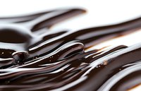 Smooth flowing dark chocolate waves create abstract pattern with glossy texture and light reflections, suitable for confectionery and dessert marketing.