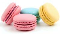 Colorful French macarons in pastel pink, mint green and yellow on white background. Sweet dessert cookies isolated for bakery menu design.