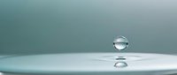 Single water droplet suspended above calm surface creating perfect sphere with reflection below against soft teal gradient background for wellness concepts.