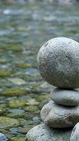 Balanced stone stack by flowing water creates peaceful zen meditation scene for wellness and mindfulness practices.