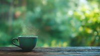 Steaming hot beverage in green ceramic cup on rustic wooden table with blurred natural green foliage background, creating peaceful morning atmosphere.
