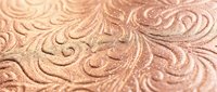 Elegant rose gold metallic surface with intricate embossed floral swirl patterns creating luxurious textured background for premium design projects.