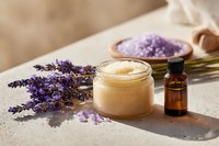 Lavender spa composition with natural scrub, aromatic oil, bath salt and fresh flowers on beige background for wellness and skincare routine.