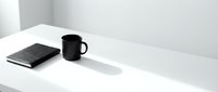 Minimalist workspace with black mug and notebook on white desk, monochrome office setup for business, productivity, and creative work environments.