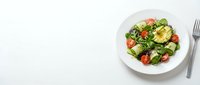 Fresh mixed green salad with cherry tomatoes, avocado and herbs served on white plate with fork, healthy eating concept for restaurant menus and cooking.