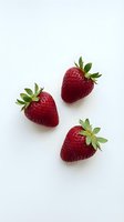 Three fresh ripe strawberries with green leaves isolated on white background for healthy eating and organic food concepts.