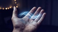 Male hand holding glowing blue energy waves with bokeh lights in dark background for technology and innovation concepts.
