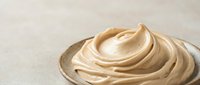 Creamy beige whipped mousse or frosting swirl on neutral background, suitable for bakery, dessert, and food packaging design projects.