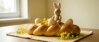 Easter braided bread with eggs and wooden bunny decoration on rustic table by sunny window for spring holiday baking and festive breakfast celebration.