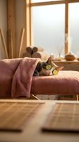 Relaxed tabby cat with cucumber slices on eyes lying on pink towel in spa wellness setting with warm natural lighting for self-care and relaxation concepts.