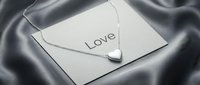 Silver heart pendant necklace on a love card, draped over elegant gray satin fabric, perfect for Valentine's Day and jewelry promotions.