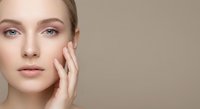 Young Caucasian woman with natural makeup touching face gently, skincare and beauty concept for cosmetic advertising and wellness campaigns.