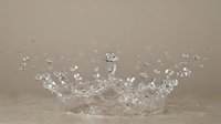 Clear water crown splash with droplets frozen in motion against neutral beige background showcasing liquid dynamics and fluid movement in macro photography.