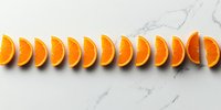 Fresh orange slices arranged in row on white marble background, bright citrus fruit pattern for healthy eating and vitamin C concept. Minimal food styling.