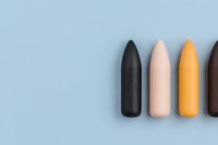 Minimalist composition of matte lipsticks in black, nude, yellow and brown shades arranged in row on light blue background. Modern beauty concept for cosmetics design.
