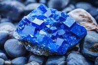 Vibrant blue chalcanthite crystal cluster formation on dark river rocks displays natural geometric patterns and mineral growth structure in macro photography.