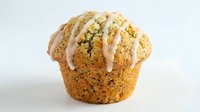 Freshly baked poppy seed muffin with white glaze drizzle on top, isolated on white background. Suitable for bakery, food, and culinary content.