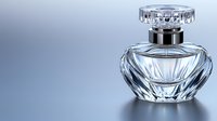 Crystal glass perfume bottle with faceted design and silver cap on reflective surface against soft blue background, luxury fragrance container for cosmetics industry.