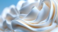 Soft swirls of white cream create elegant waves and curves in macro photography, showing delicate texture and smooth gradients for dessert and beauty product designs.