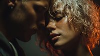 Intimate moment between young couple with curly blonde woman and dark-skinned man in warm golden lighting creating romantic atmosphere for relationship content.