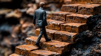 Businessman climbing old brick stairs, symbolizing career growth and overcoming challenges. Dark suit figure ascending weathered stone steps in dramatic lighting.