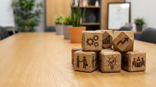 Wooden business concept blocks with corporate icons on office desk representing teamwork, innovation, strategy and leadership development.