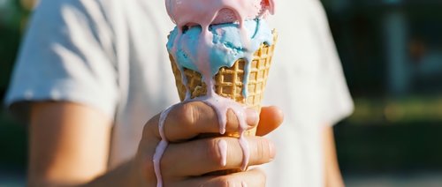 Person wearing white t-shirt holding melting ice cream cone with blue topping in sunny outdoor setting, ideal for summer, dessert, and food-related designs.