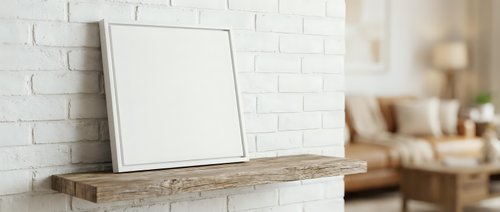 Blank white canvas frame mockup on wooden shelf against brick wall in modern living room interior for artwork display and home decor presentation.