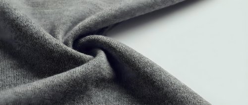 Soft gray fabric texture with natural folds and wrinkles, showcasing textile material detail for fashion design, upholstery and interior decoration projects.