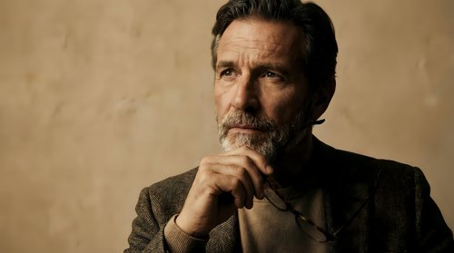Mature businessman with mustache in contemplative pose against textured background. Professional portrait for corporate and leadership concepts.