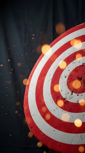 Red and white dartboard target with glowing orange lights and sparks on dark background for business goals and achievement concepts.