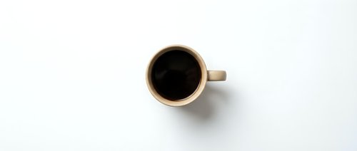 Beige coffee cup with black coffee viewed from above on white background, minimalist flat lay composition for cafe branding and morning beverage concepts.