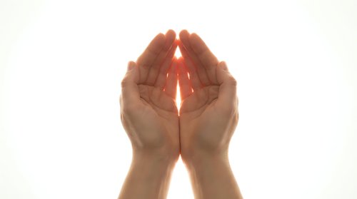 Cupped hands holding glowing light beam on white background. Spiritual energy, healing power, protection concept for wellness and meditation designs.