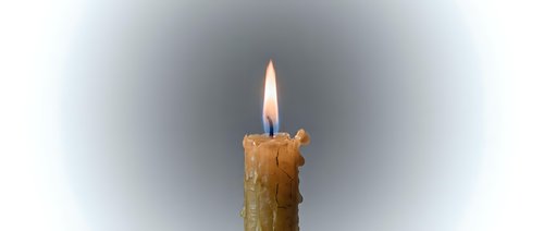 Burning wax candle with melted drips and bright flame on gradient background for relaxation, meditation, spa treatments, romantic atmosphere and cozy home decor.