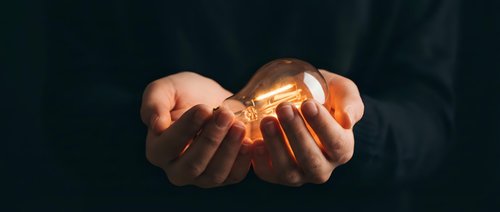 Hands holding glowing light bulb symbolizing innovation, creativity, bright ideas, inspiration and entrepreneurship for business concepts.
