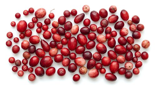 Fresh red cranberries scattered on white background, organic superfood berries for healthy eating, cooking ingredients, holiday recipes and natural nutrition.