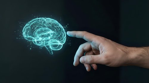 Human hand reaching toward glowing digital brain hologram on dark background representing artificial intelligence, neuroscience and cognitive technology concepts.