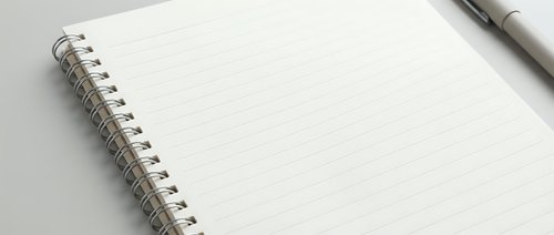 Open spiral notebook with dotted grid pages and pen for writing, planning, journaling, note-taking, sketching, bullet journaling and office work.