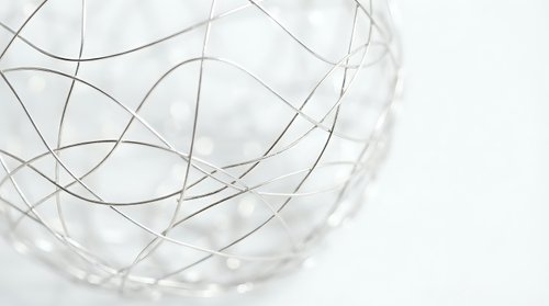 Abstract geometric wire sculpture with curved lines creating organic flowing patterns on white background for modern interior design.