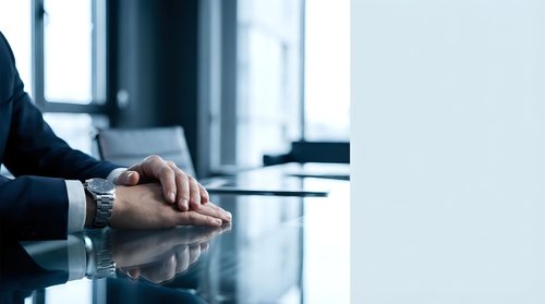 Professional businessman hands folded on conference table in modern office boardroom during corporate meeting or negotiation session.