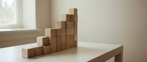 Wooden blocks stacked in ascending staircase pattern on table, representing growth, progress, and business development concepts for corporate presentations.