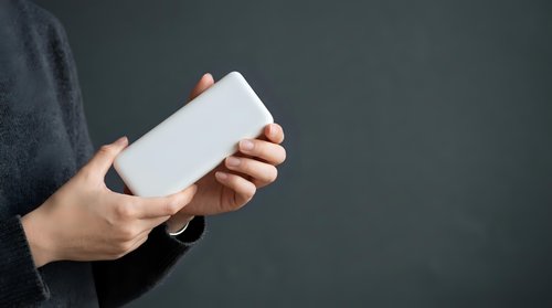 Person of South Asian descent holding blank white rectangular card or device mockup against gray background for branding and marketing purposes.