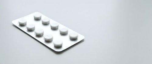 White medication pills in blister pack on clean background for pharmaceutical and healthcare concepts.