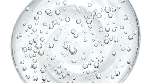 Close-up of water droplets and bubbles on a clear glass surface, ideal for backgrounds, skincare, cosmetics, and wellness product marketing.