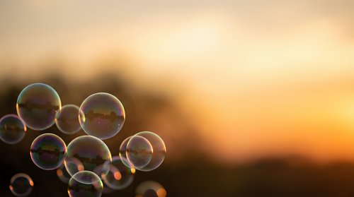 Soap bubbles floating against warm golden sunset sky creating dreamy atmospheric scene for relaxation and mindfulness concepts.