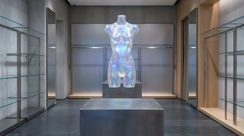 Holographic female mannequin display in modern luxury retail showroom with glass cases and contemporary lighting for fashion presentation.