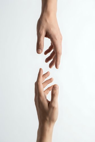 Two hands reaching toward each other on white background symbolizing connection, help, support, teamwork and human interaction for business concepts.