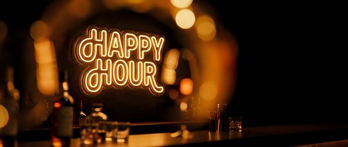 Neon happy hour sign glowing in warm orange light with blurred bar background creating cozy nightlife atmosphere for restaurant and pub promotions.
